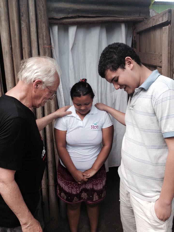 Elderly man and a boy giving healing prayer to a woman